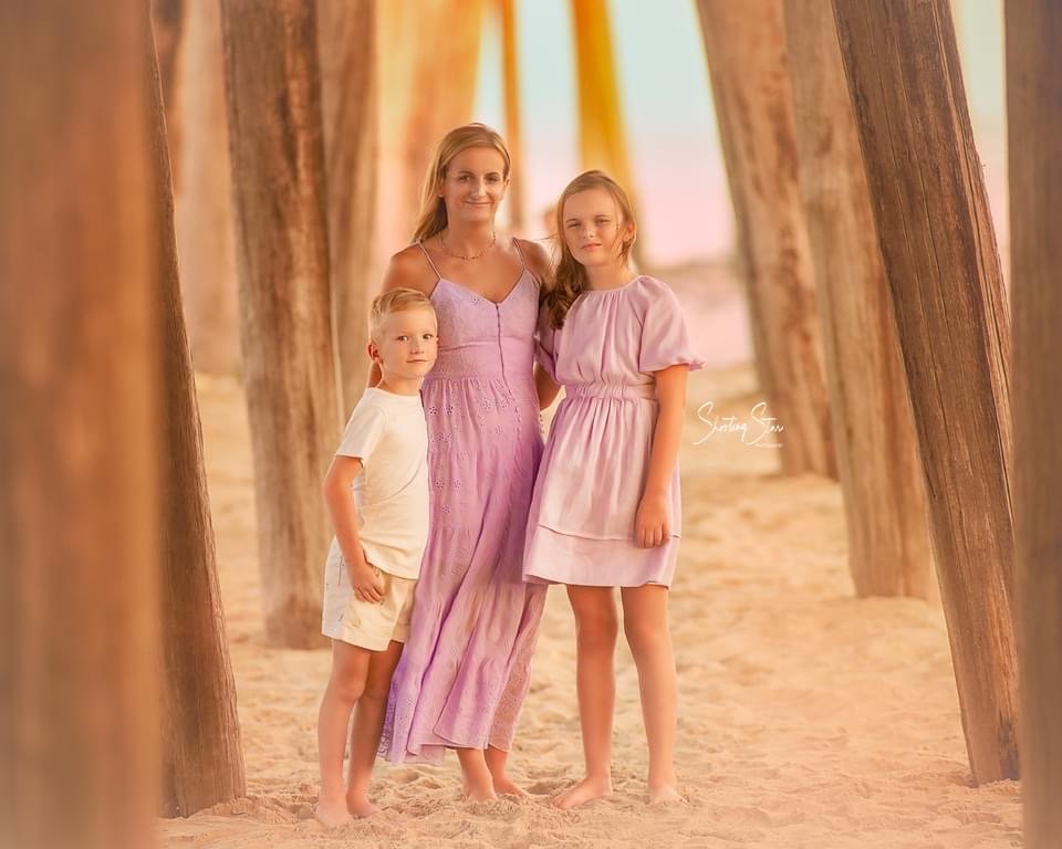 Mother with her children under the fishing pier during a family photography session in Ocean City NJ