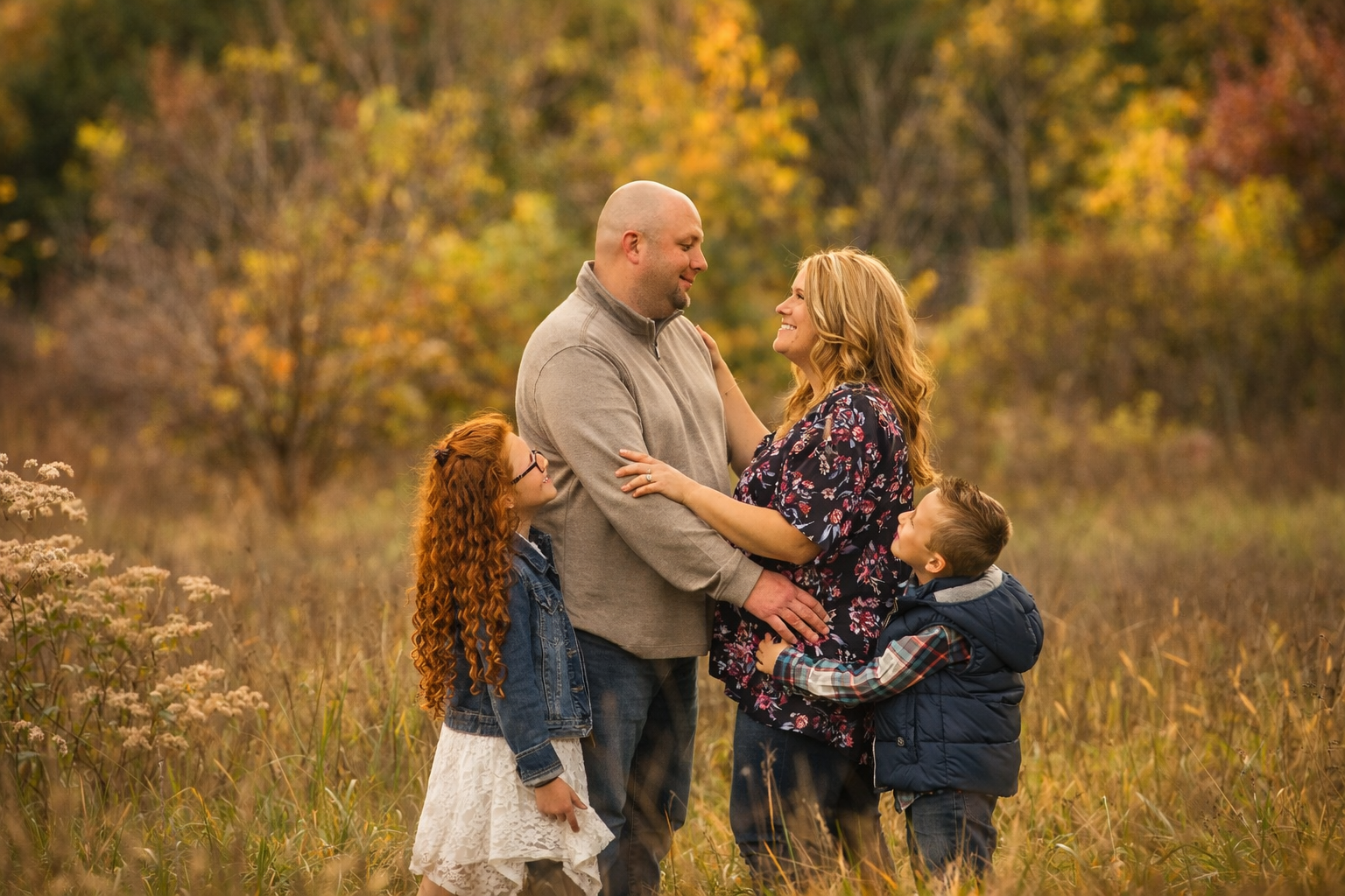 Family of four smiling together surrounded by colorful fall foliage in Sewell, New Jersey during a South Jersey family photography session.