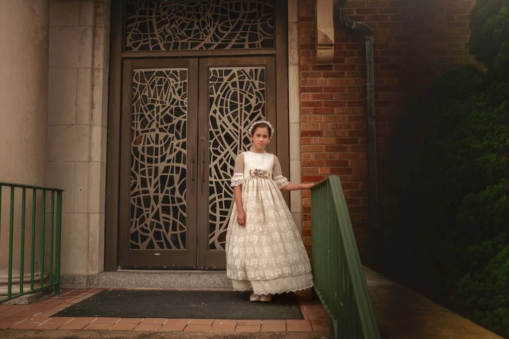First Holy Communion portrait of a young girl wearing a vintage Communion dress photographed outside her church