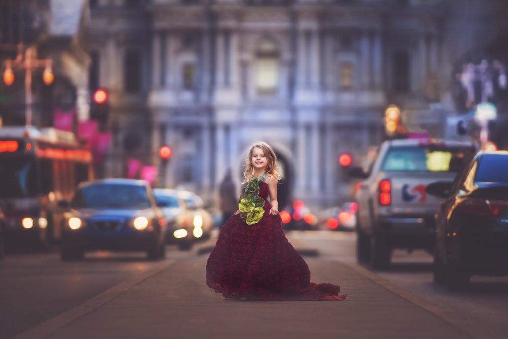 Fine art child portrait of a young girl posing in a red dress on Broad Street in Philadelphia