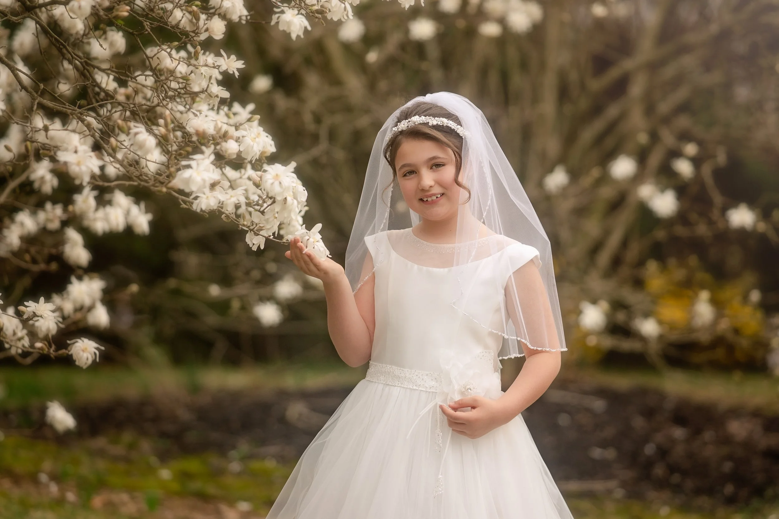 girl with cherry blossoms in the spring for her first holy communion portraits with a philadelphia photographer