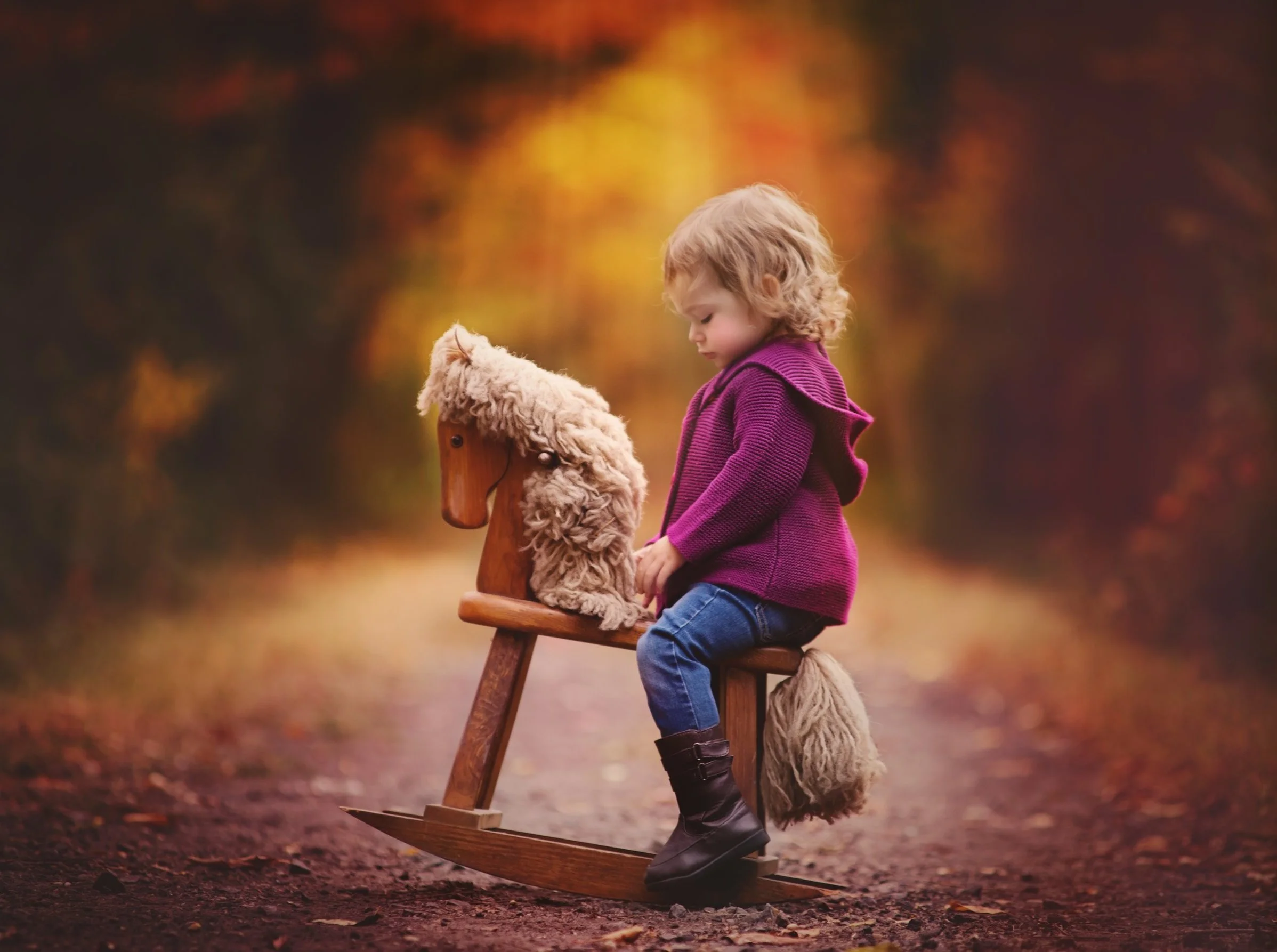 toddler sitting on rocking horse during whimsical portrait session in New Jersey