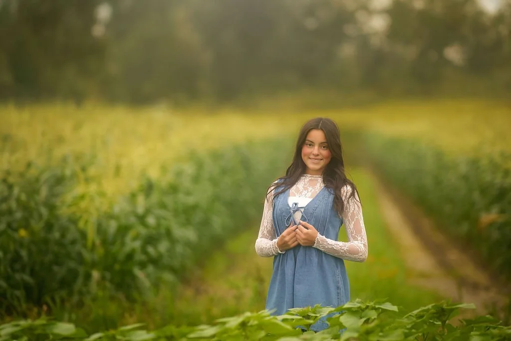 Teen girl standing in a flower field during an outdoor senior portrait session in South Jersey with soft natural light.