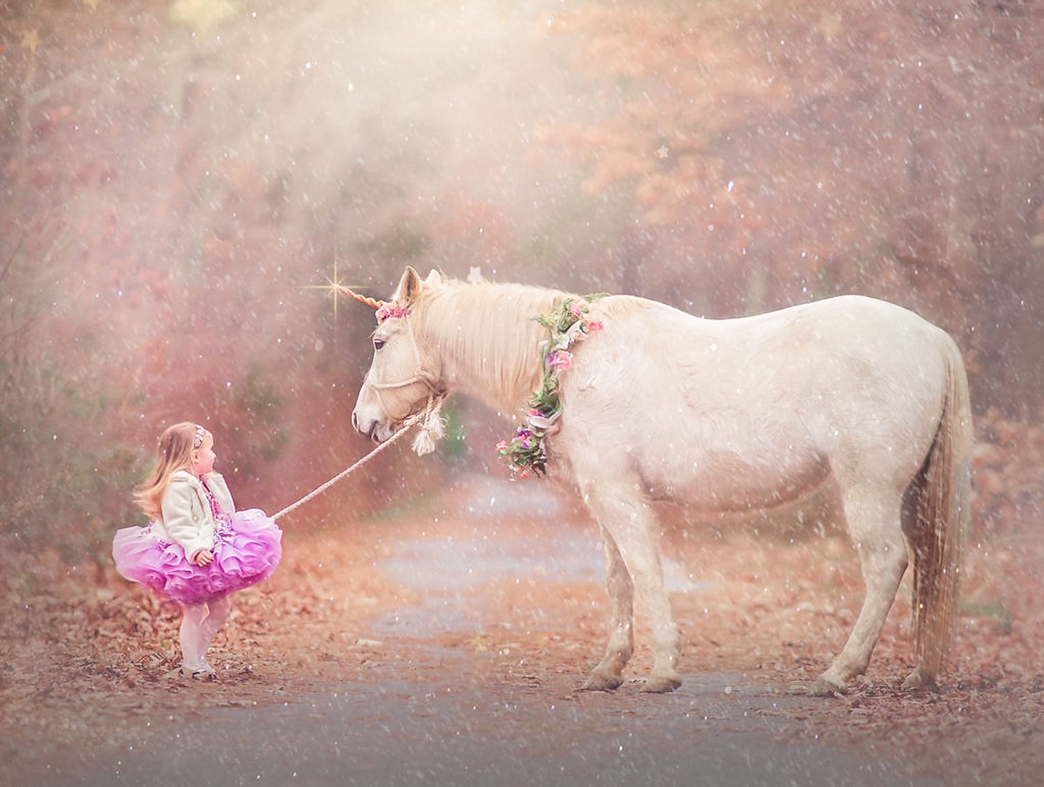 A young girl in a pink dress holding onto her unicorn during a winter unicorn portrait session.