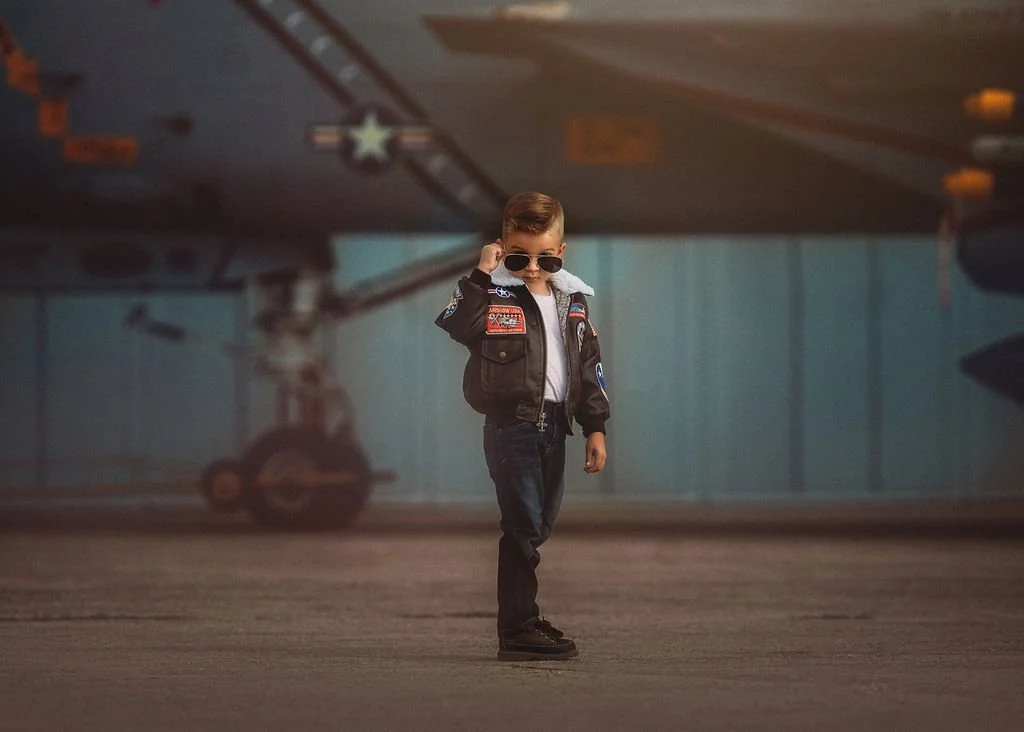 Kid wearing aviator glasses posing by airplane during Top Gun inspired photoshoot in New Jersey