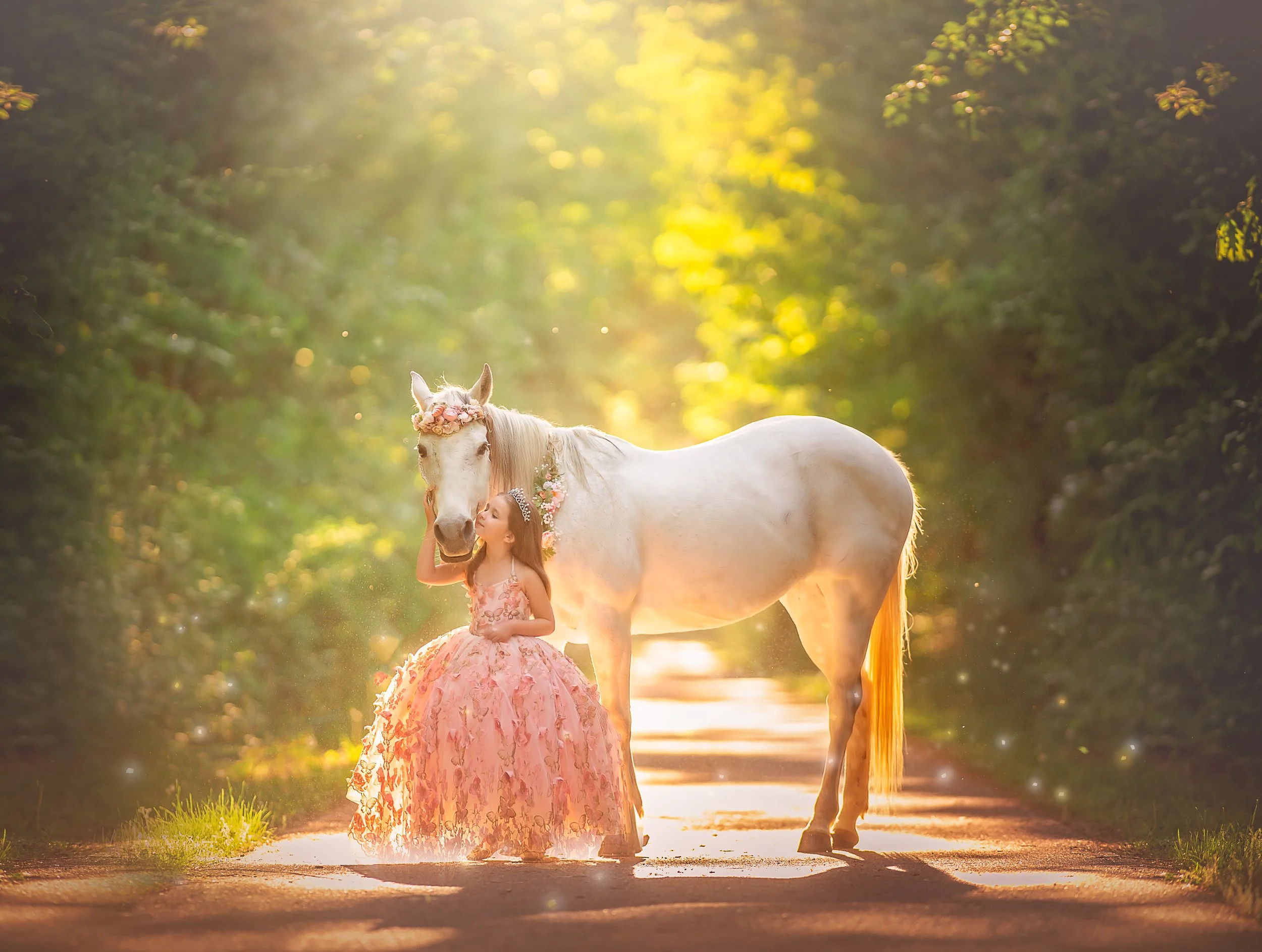 A little girl in a flowing blush dress shares a quiet moment with a white unicorn on a glowing forest path, phootgraphed in warm light in New Jersey