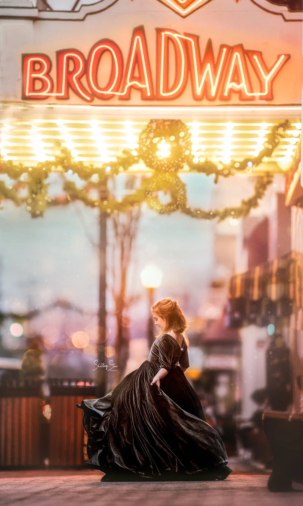 Child twirling under the Broadway theater sign in Pitman NJ during golden hour