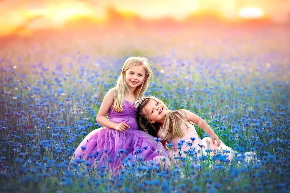 Sisters in a field of vibrant cornflowers during a dreamy wildflower session in New Jersey, captured by a NJ portrait photographer.