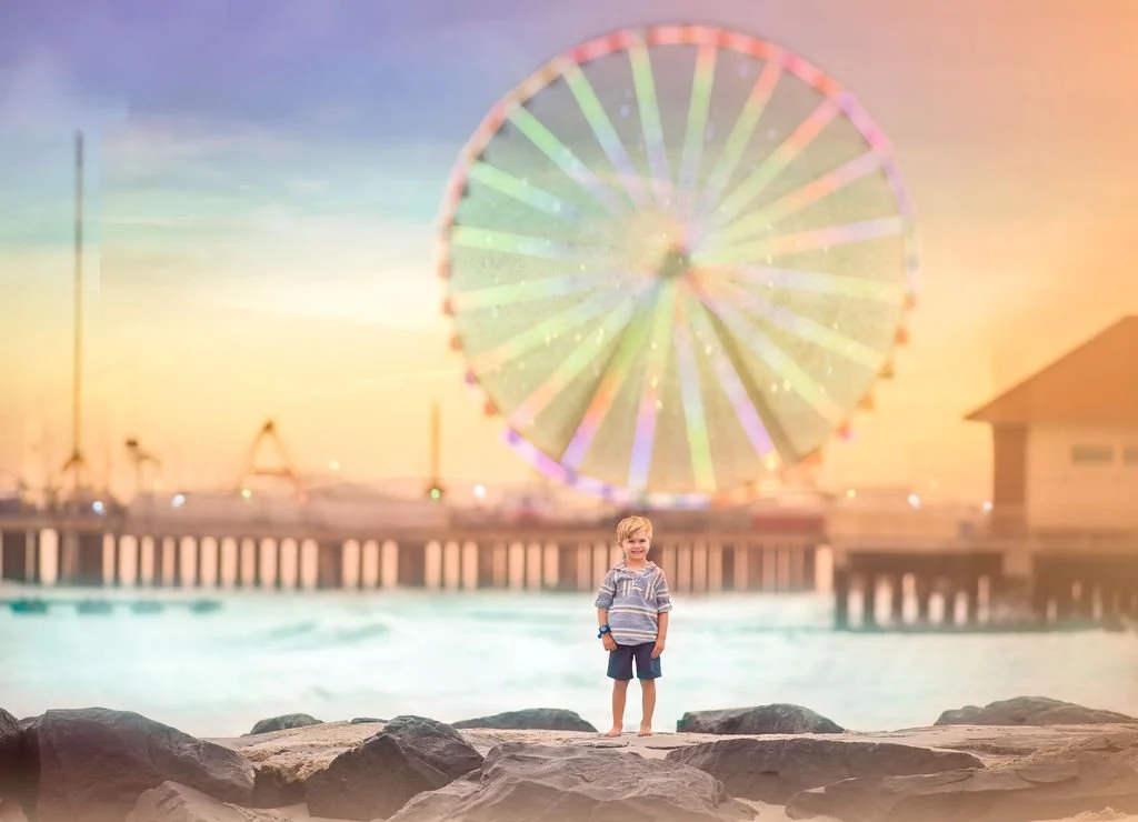 Little boy smiling in front of the Ferris wheel at Steel Pier during a family beach session in Atlantic City NJ.