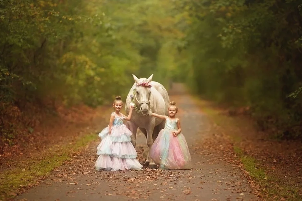 Two girls wearing rainbow dresses posing with a unicorn during a South Jersey unicorn photography session