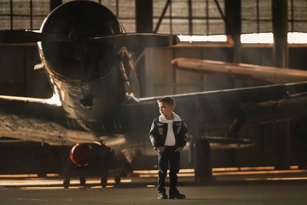 Child in bomber jacket posing in cinematic style during aviation photoshoot near Cape May New Jersey