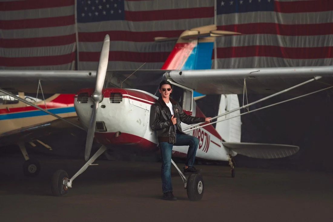 a cinematic teen fine art portrait photographed in an aviation setting, designed to reflect confidence, individuality, and a strong editorial presence.