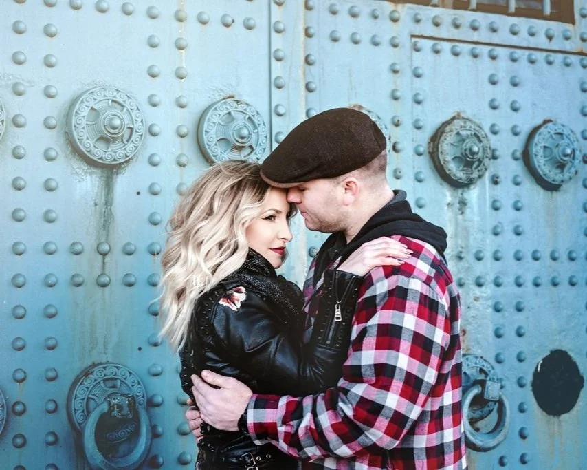 A tender moment between an engaged couple near the base of the Benjamin Franklin Bridge during their winter engagement session at Race Street Pier