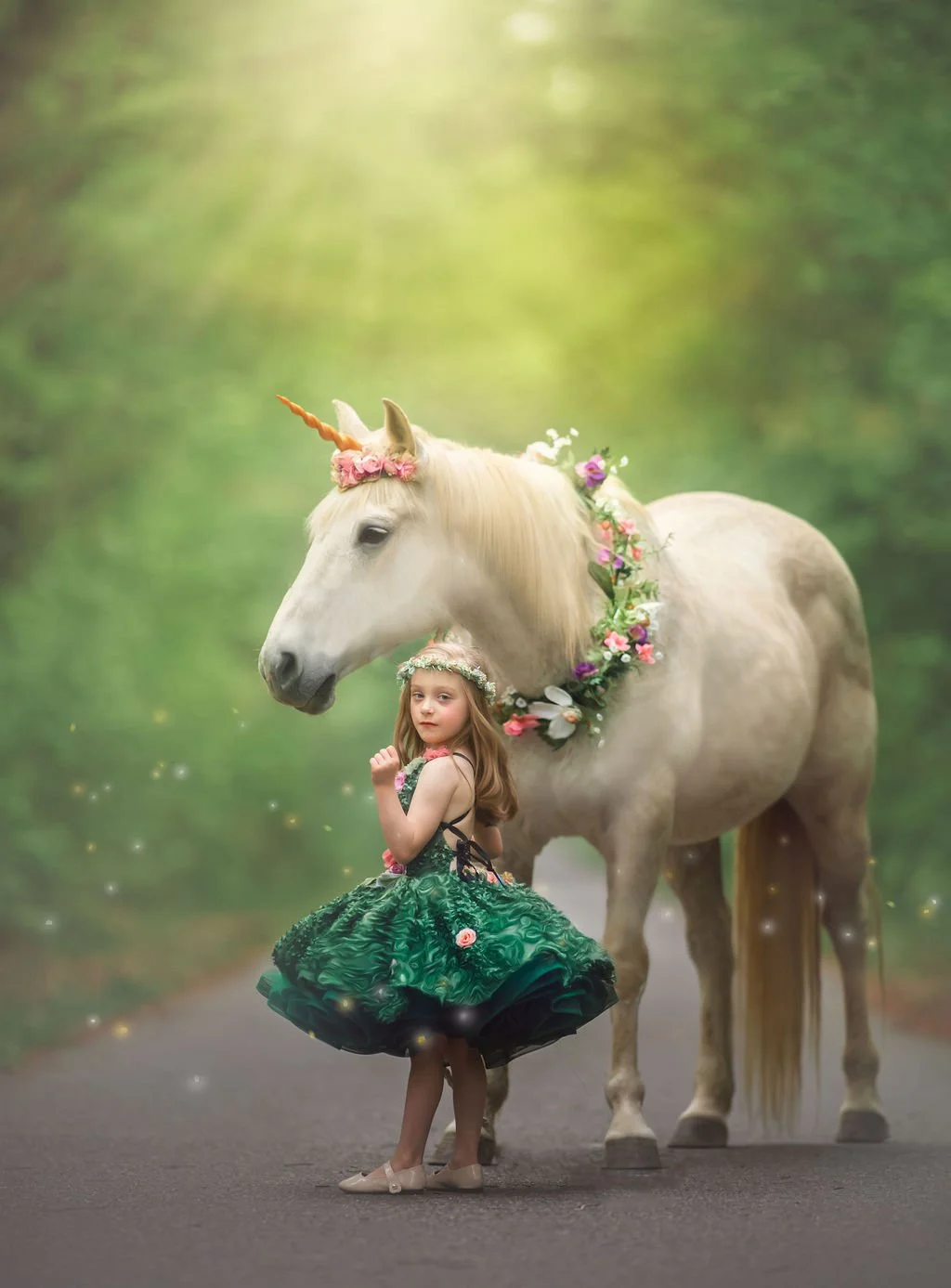 A luxury unicorn portrait of a child in an emerald green gown standing beside a real unicorn, photographed in natural light to create a timeless, storybook-style fine art image for families throughout the Northeast