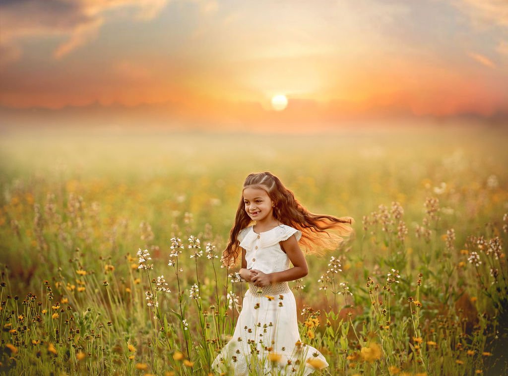 Young girl twirling and laughing in a wildflower field during a family maternity photography session in South Jersey.