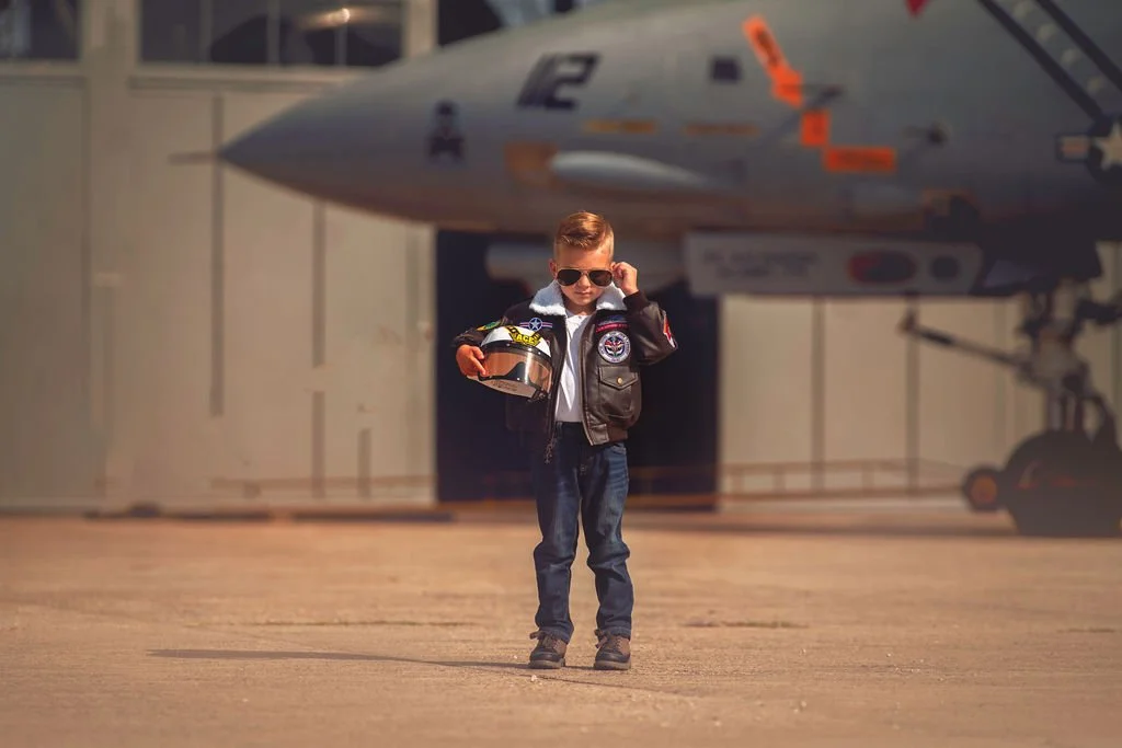 Child holding pilot helmet posing in front of jet at Naval Air Station Wildwood aviation museum New Jersey