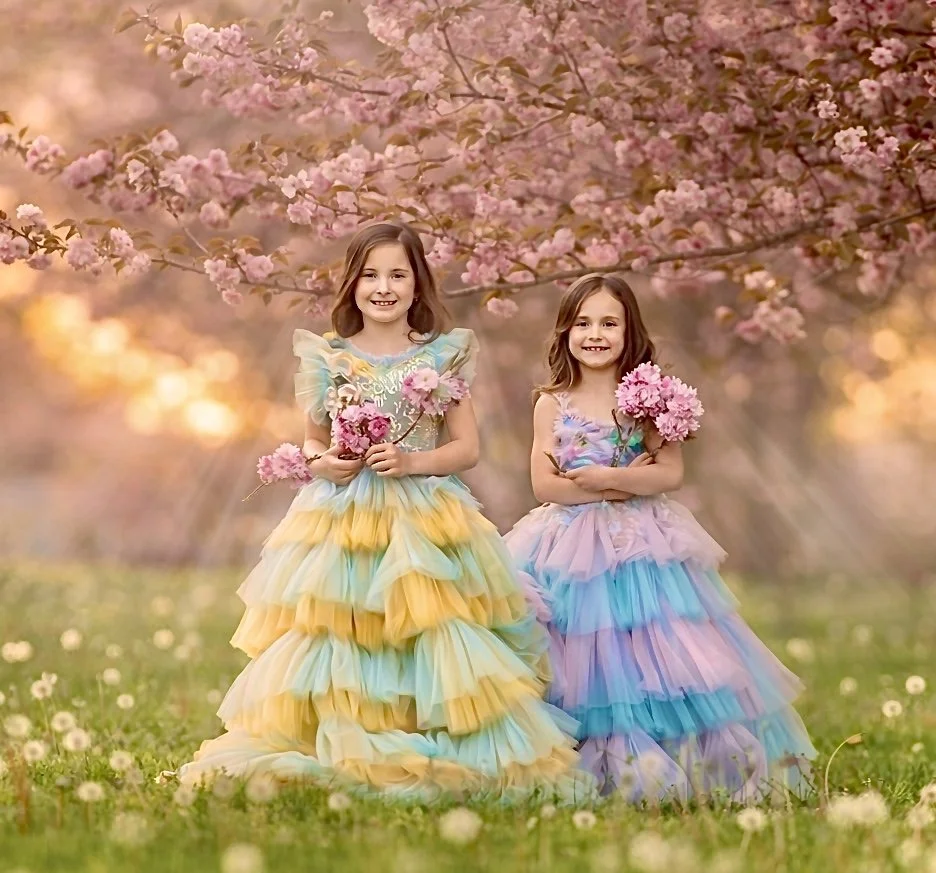 Two sisters standing under blooming cherry blossoms during a spring portrait session in Cherry Hill, New Jersey.