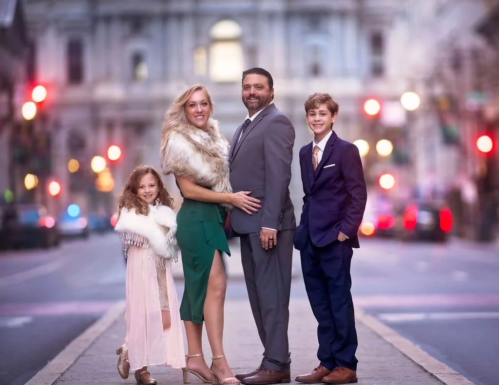 Family portrait photographed in Center City Philadelphia with classic city architecture in the background.
