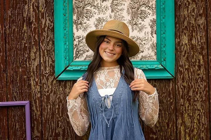 Teen girl smiling during a senior portrait session with a rustic wood background near Philadelphia and South Jersey.