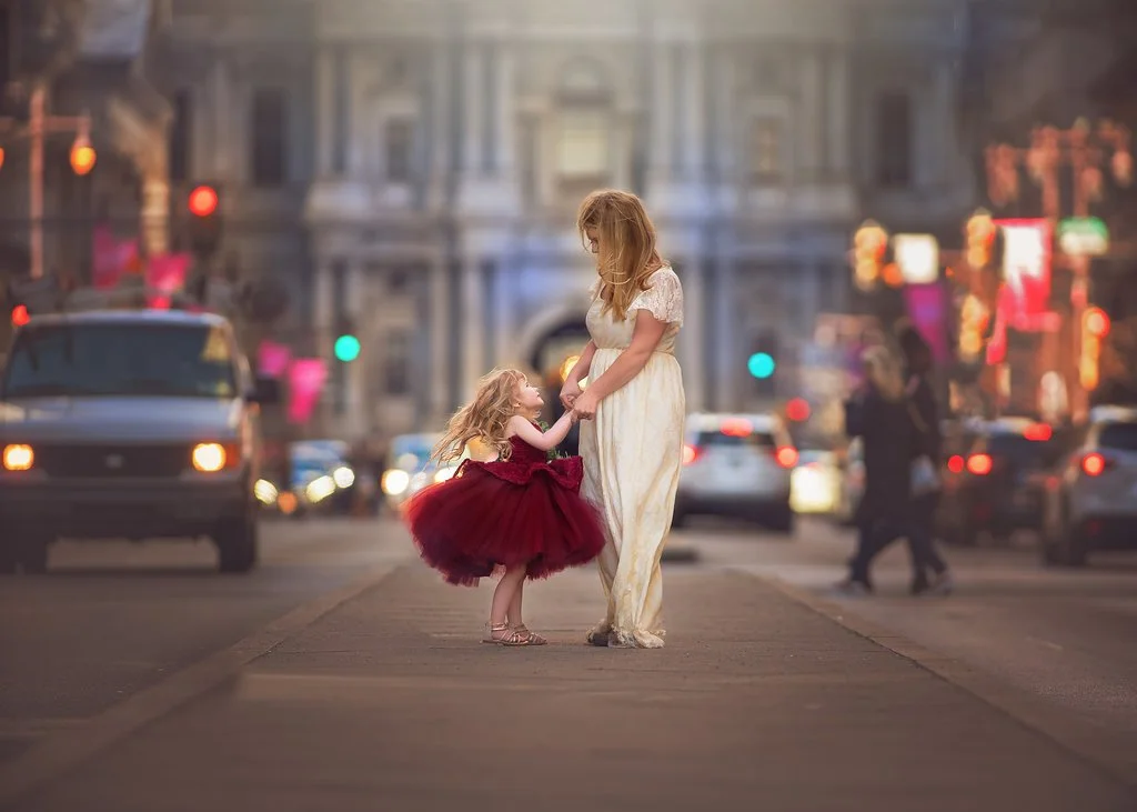 Fine art family portrait of a mother and daughter sharing a quiet moment on Broad Street in Philadelphia with wind moving through their hair