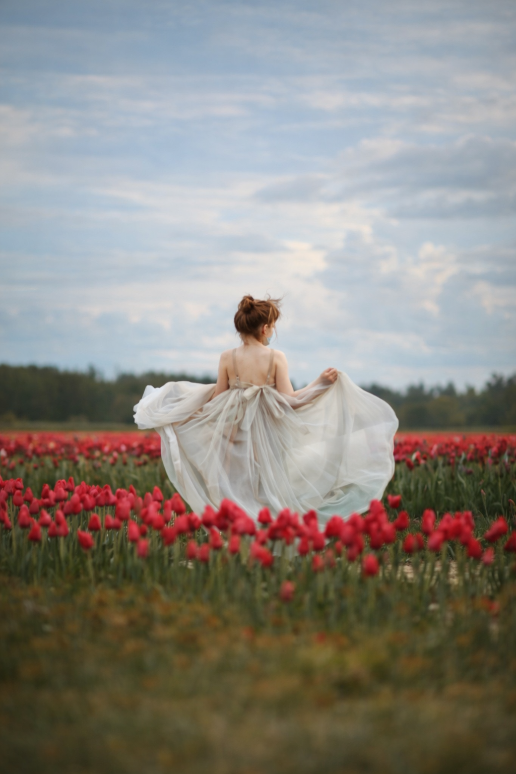 A young girl in a silver dress standing in a tulip field, photographed as a fine art portrait in New Jersey.