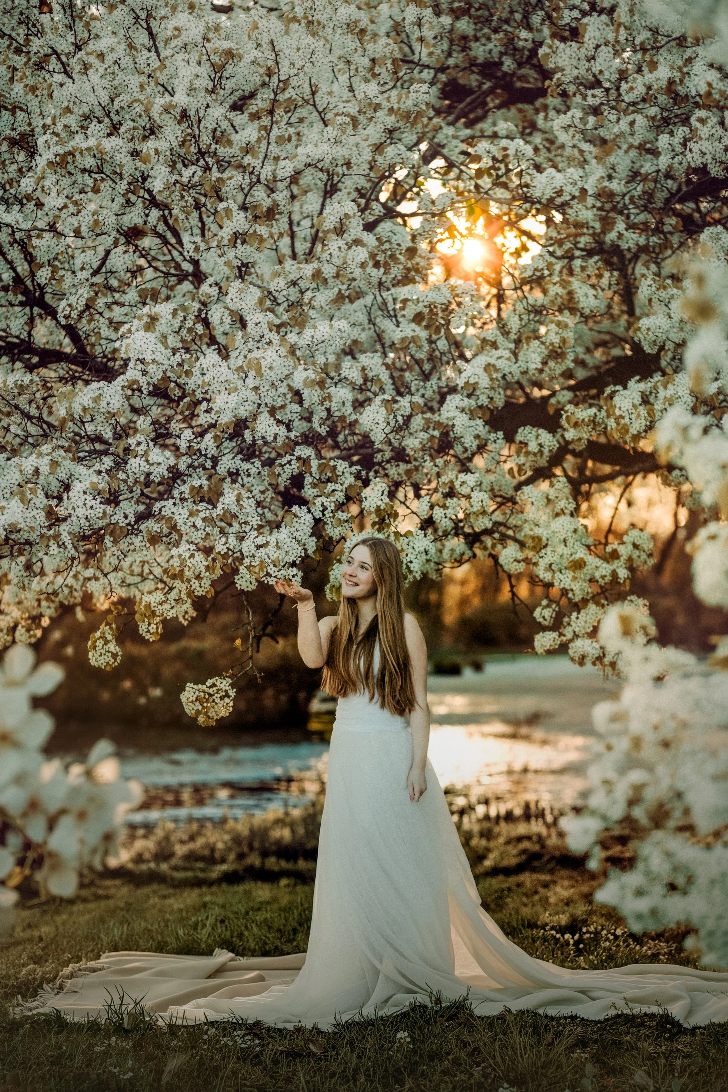 Teen girl laughing in white pear blossoms during a natural light portrait session in South Jersey