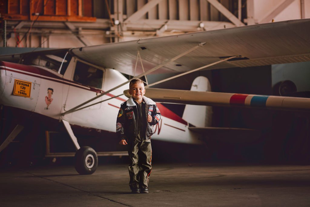 Smiling child standing in front of Cessna airplane during aviation photoshoot near Cape May New Jersey