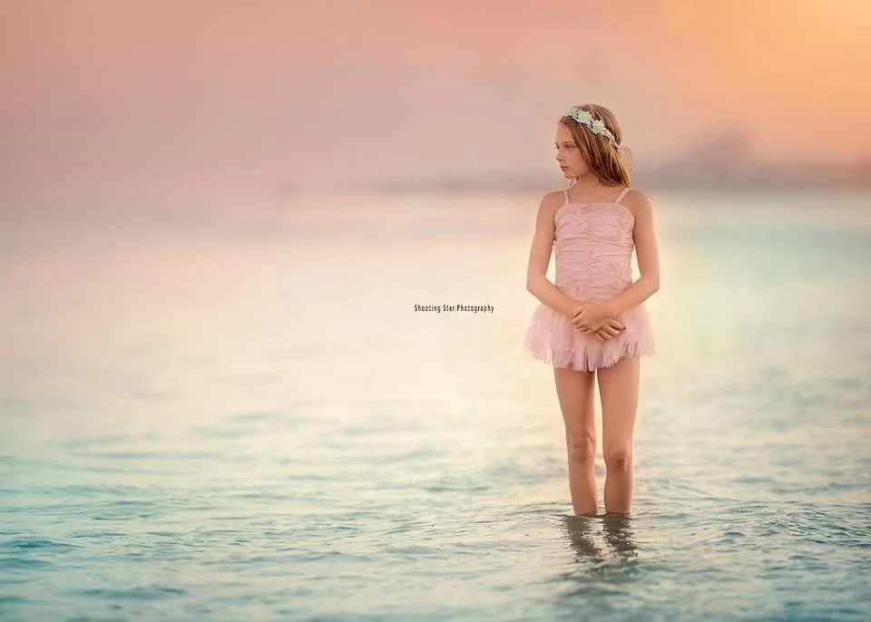 Young girl standing in shallow water at sunset during a Cape May family portrait session