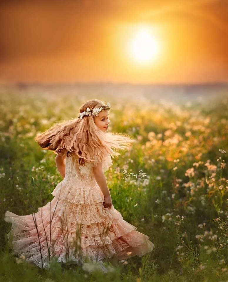 Young girl twirling in a wildflower field during a golden hour photoshoot in South Jersey