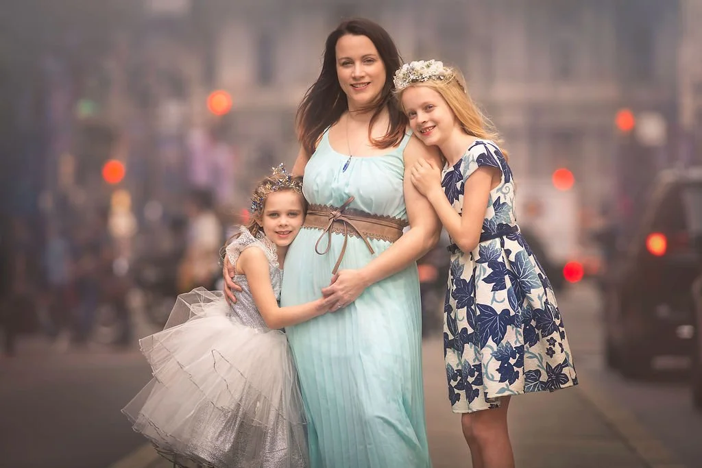 A mother posing with her two daughters during a family portrait session on Broad Street in Philadelphia.