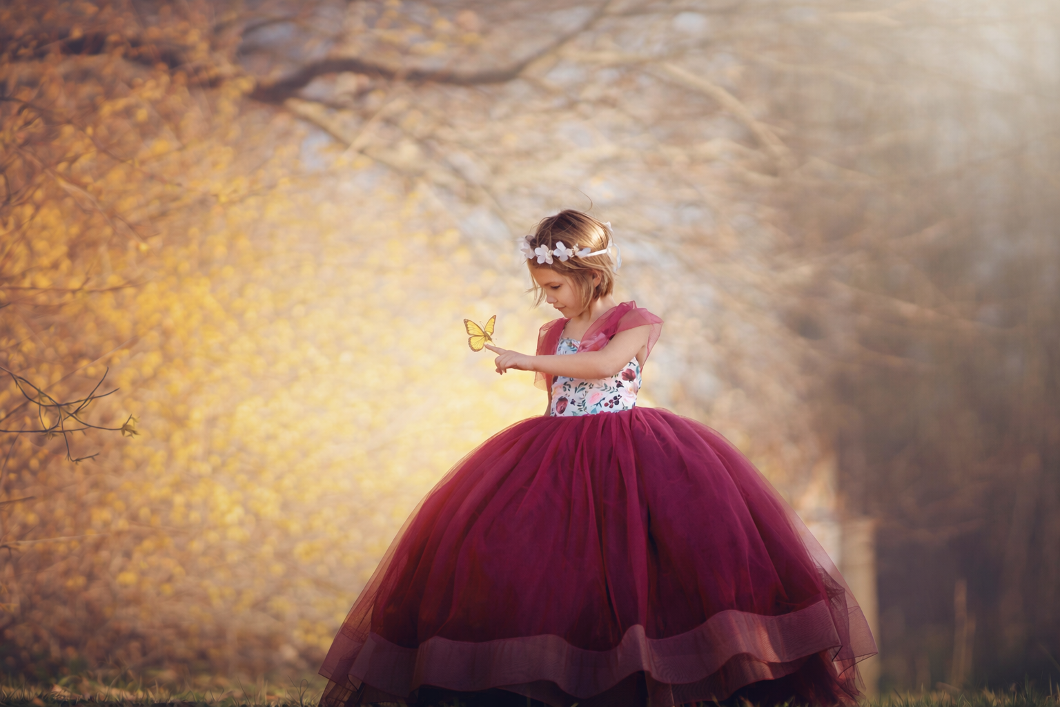 A child interacts with a butterfly during a dreamy early spring portrait session, surrounded by soft light and delicate blooms in South Jersey.