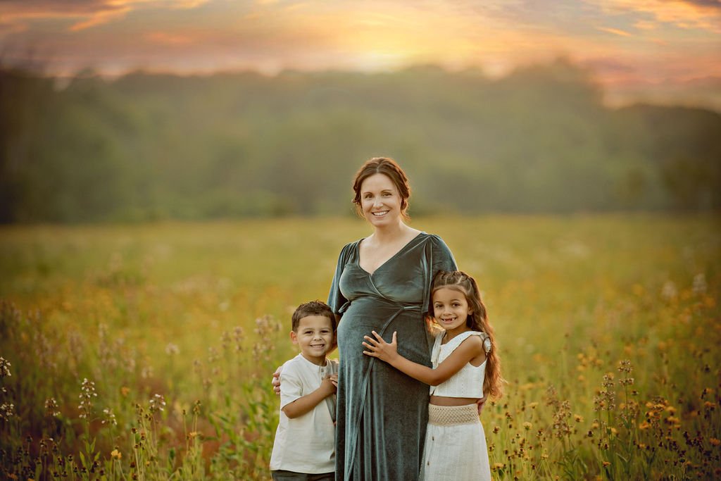 Pregnant mother with her two children standing together in a wildflower field during a family maternity photography session in South Jersey.