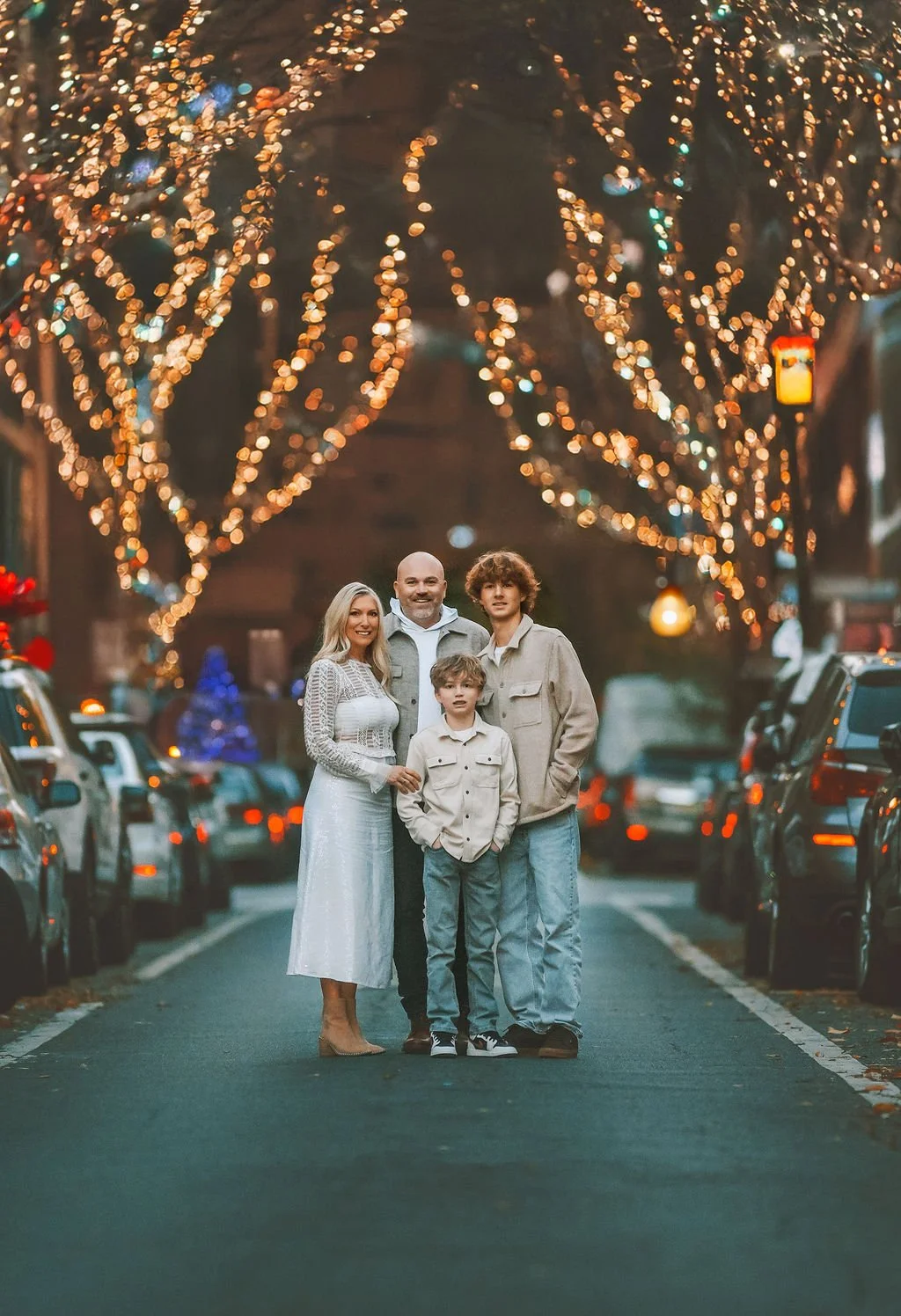 Family standing together under warm holiday lights during a winter fine art portrait session