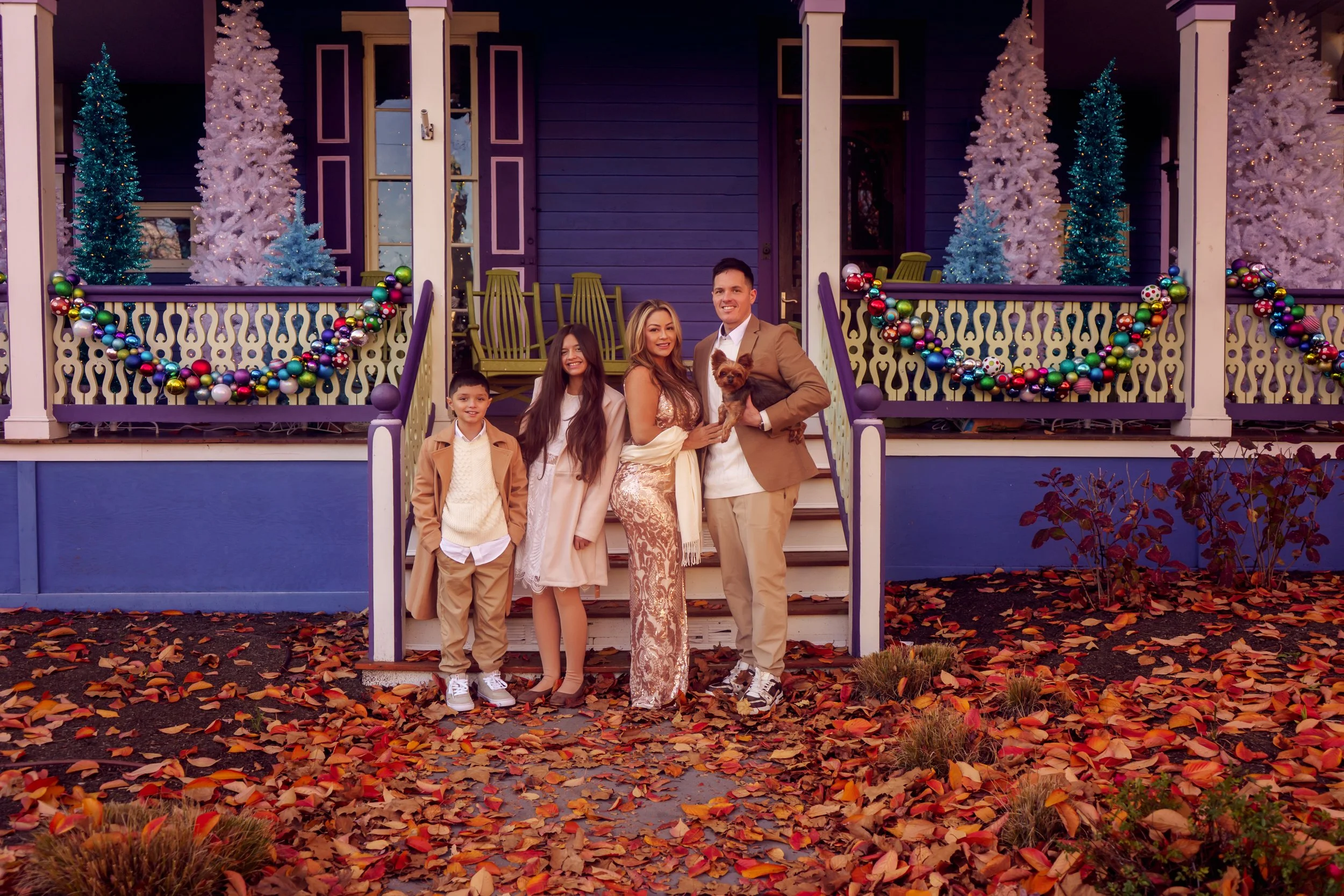Family posing together in front of a historic Victorian house during a Cape May family portrait session