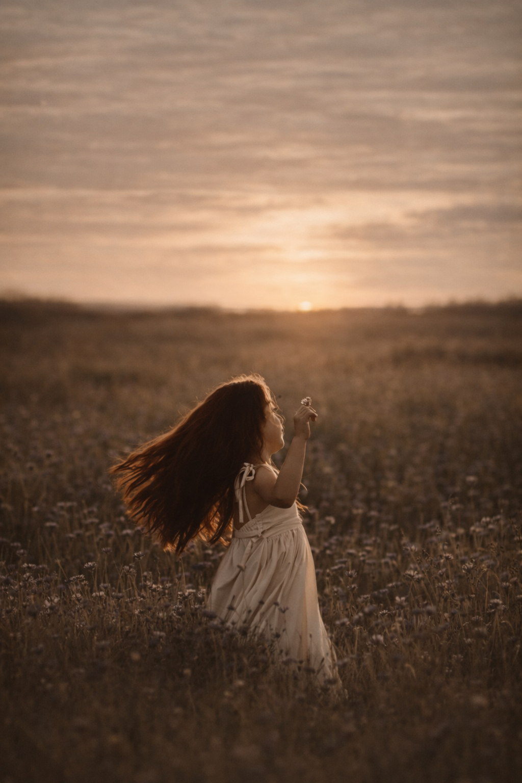 Young girl twirling in a field during a seasonal portrait session in South Jersey, photographed in soft natural light with warm earthy tones