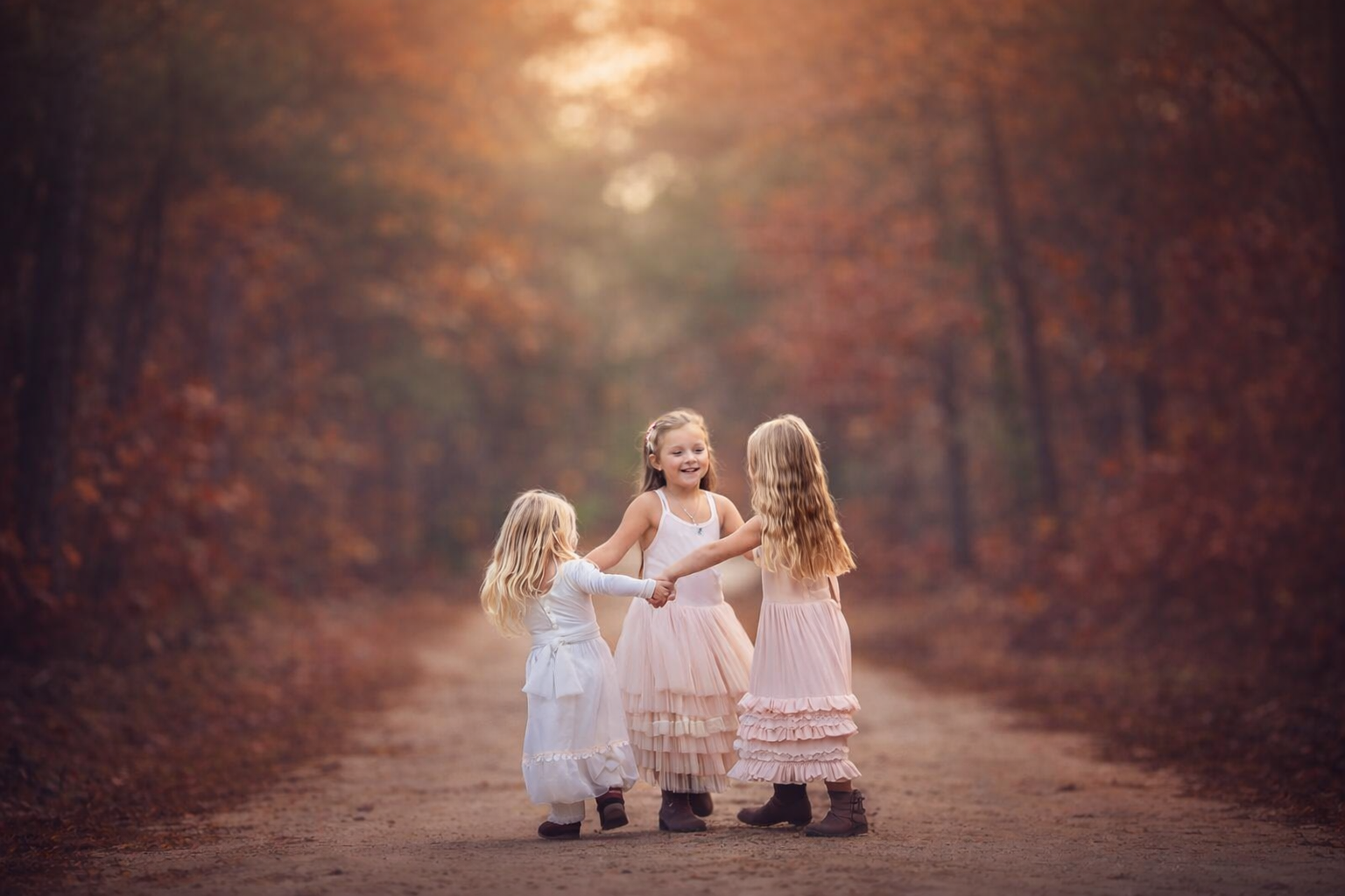 Children laughing and spinning in a circle together in a wooded South Jersey location during a family photography session.