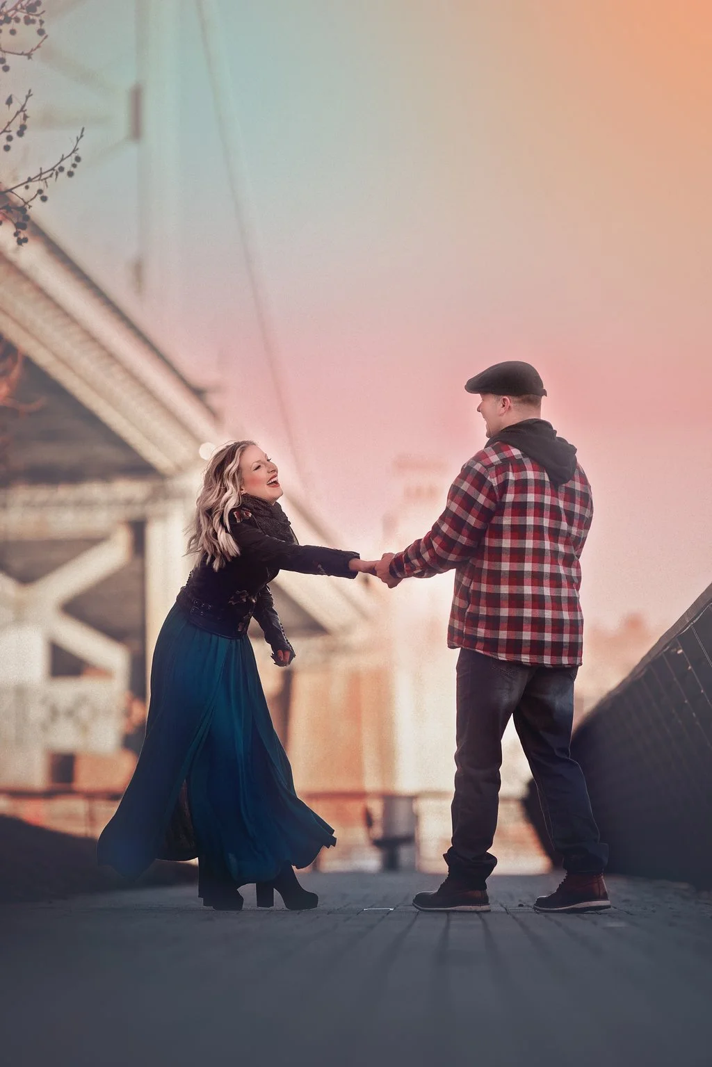 A natural, playful moment as an engaged couple laughs together at Race Street Pier with the Benjamin Franklin Bridge in the background