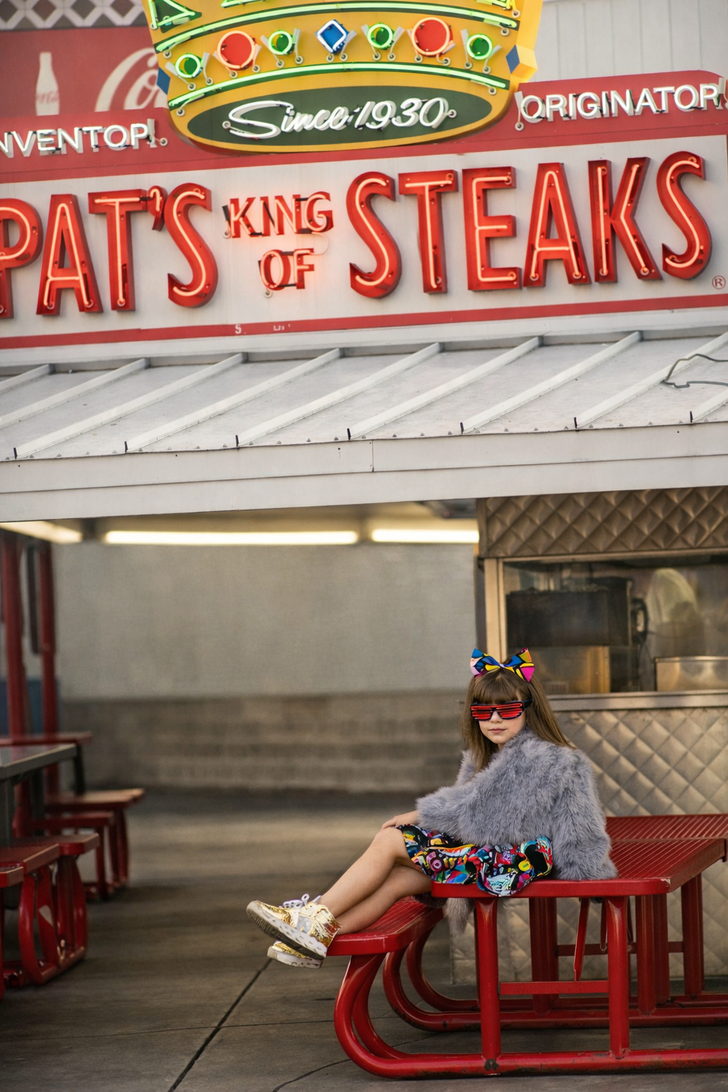 a girl posing outside of pats steaks in philadelphia for a portrait and cheesteak showdown with shooting star photography