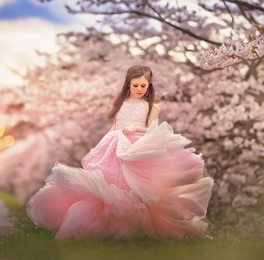 Little girl twirling under cherry blossoms during a spring portrait session in New Jersey