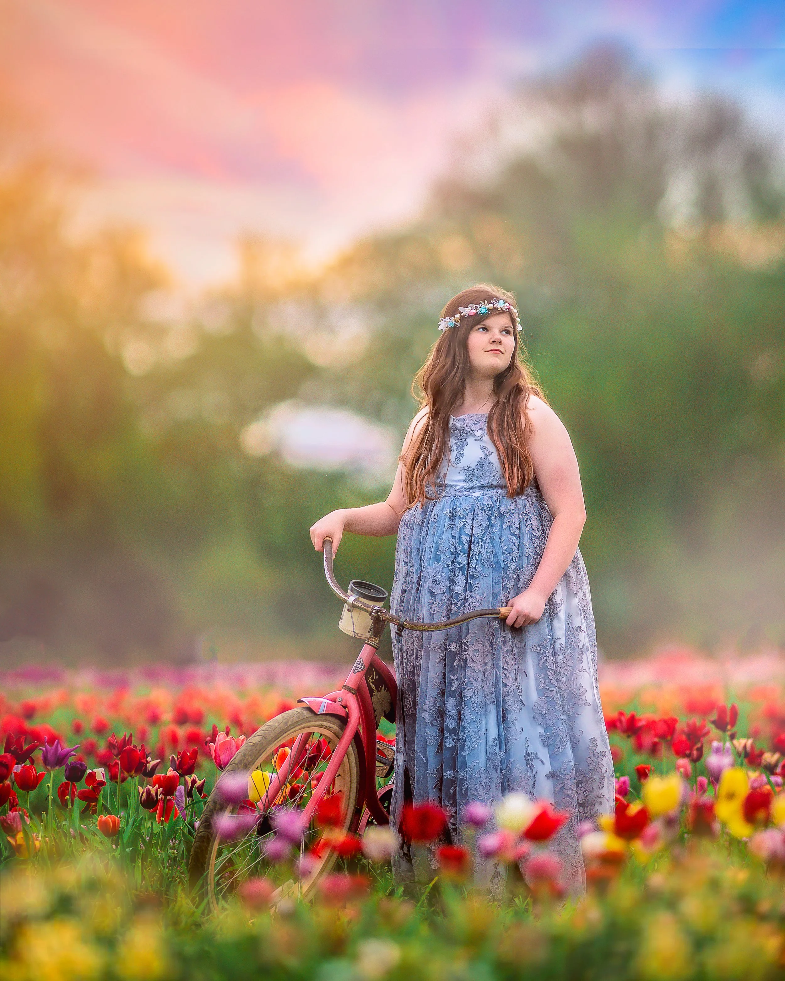 A teen girl wearing a stunning silver couture dress, gracefully posing in the colorful tulip fields at Dalton Farms in South Jersey, surrounded by the vibrant blooms.