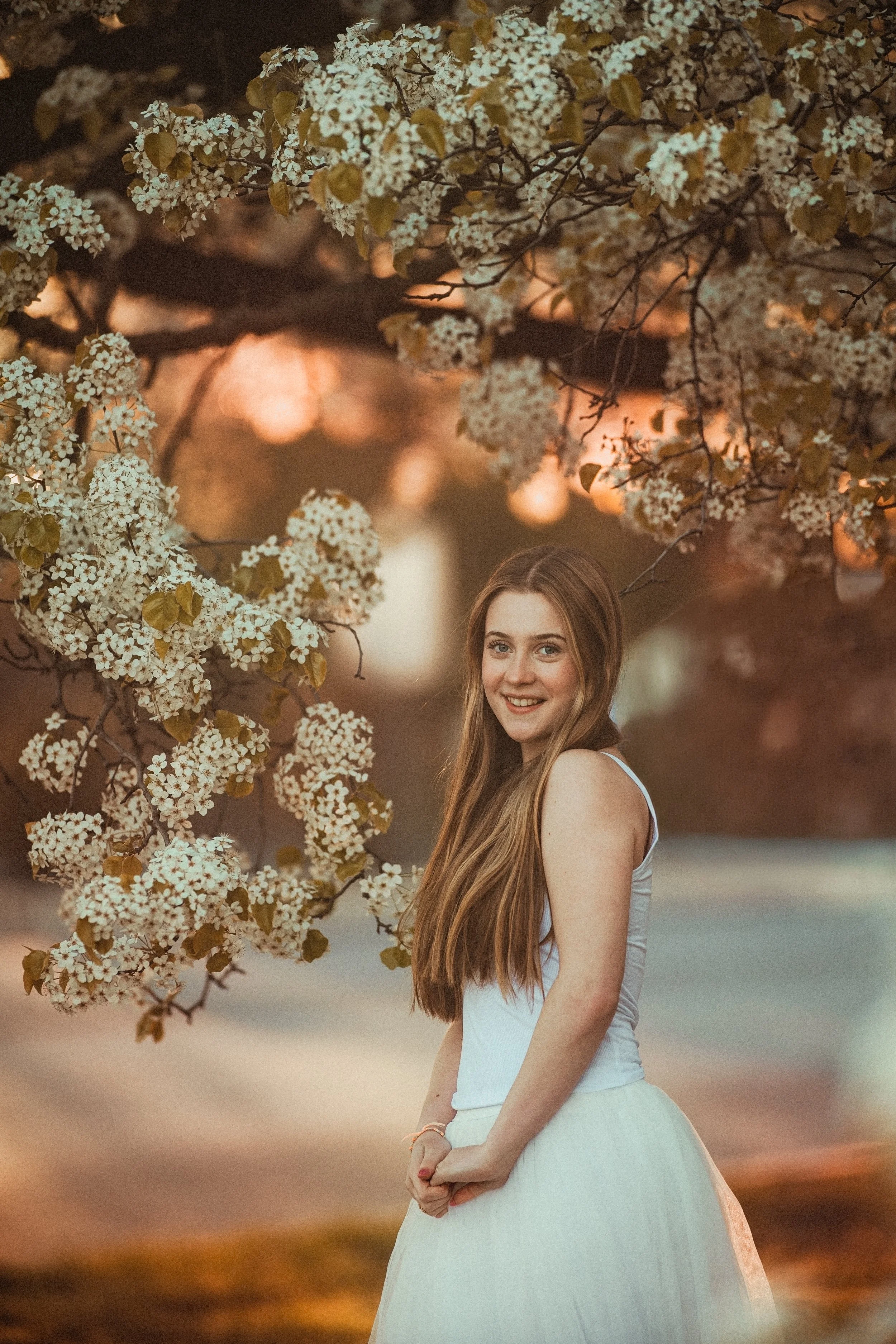 Teen girl walking through pear blossom trees in Westville NJ during a soft, natural spring senior photo session