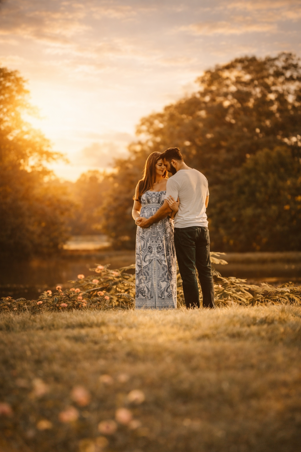 Expecting couple embracing during a golden hour maternity photography session in warm sunset light