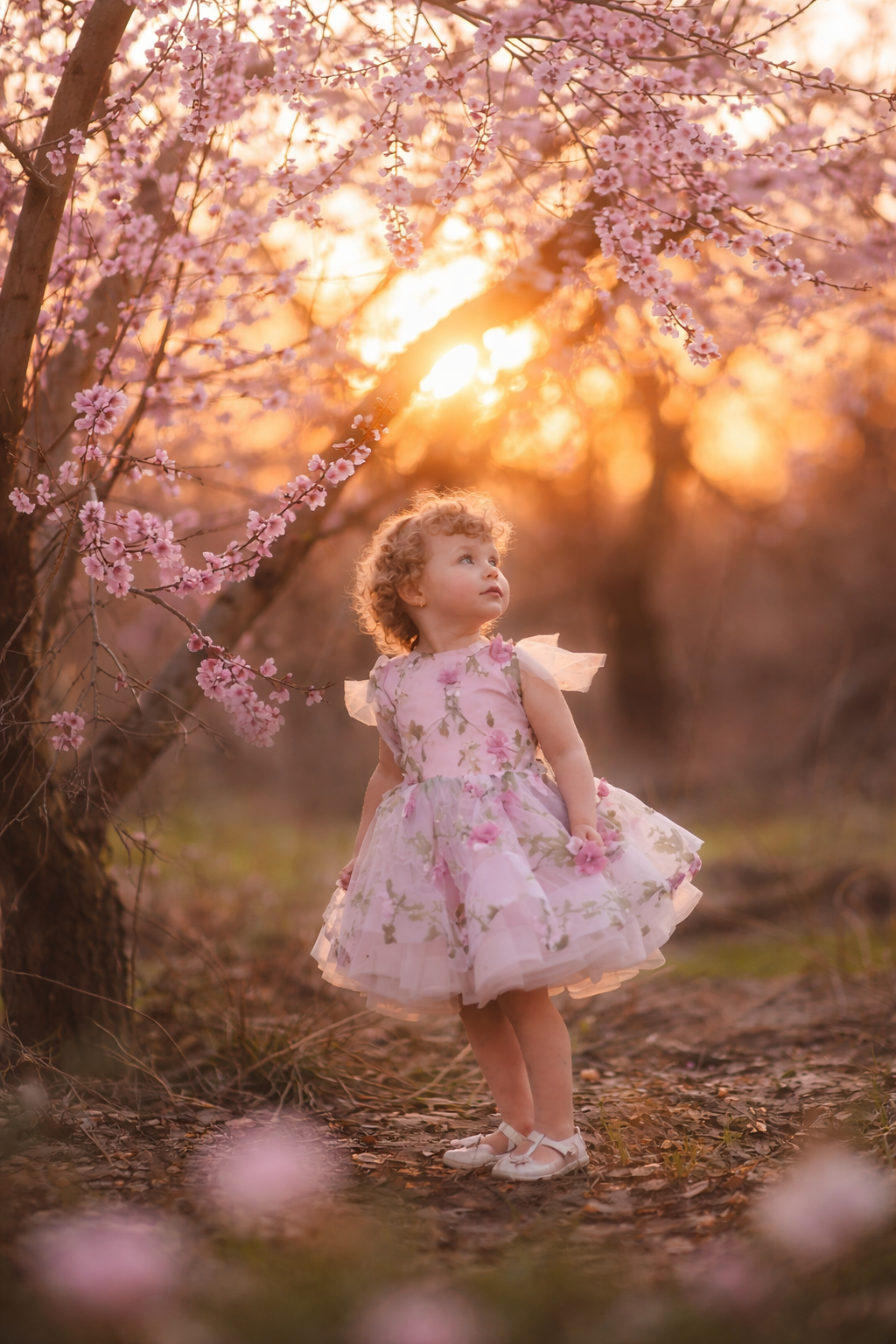 A soft profile portrait of a toddler girl photographed at sunset among peach orchard trees, captured during a fine art seasonal portrait session in New Jersey.