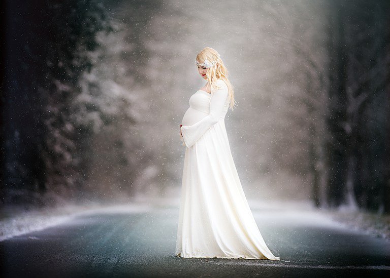 Fine art maternity portrait of a pregnant woman in a flowing white gown photographed outdoors in soft light by a South Jersey maternity photographer