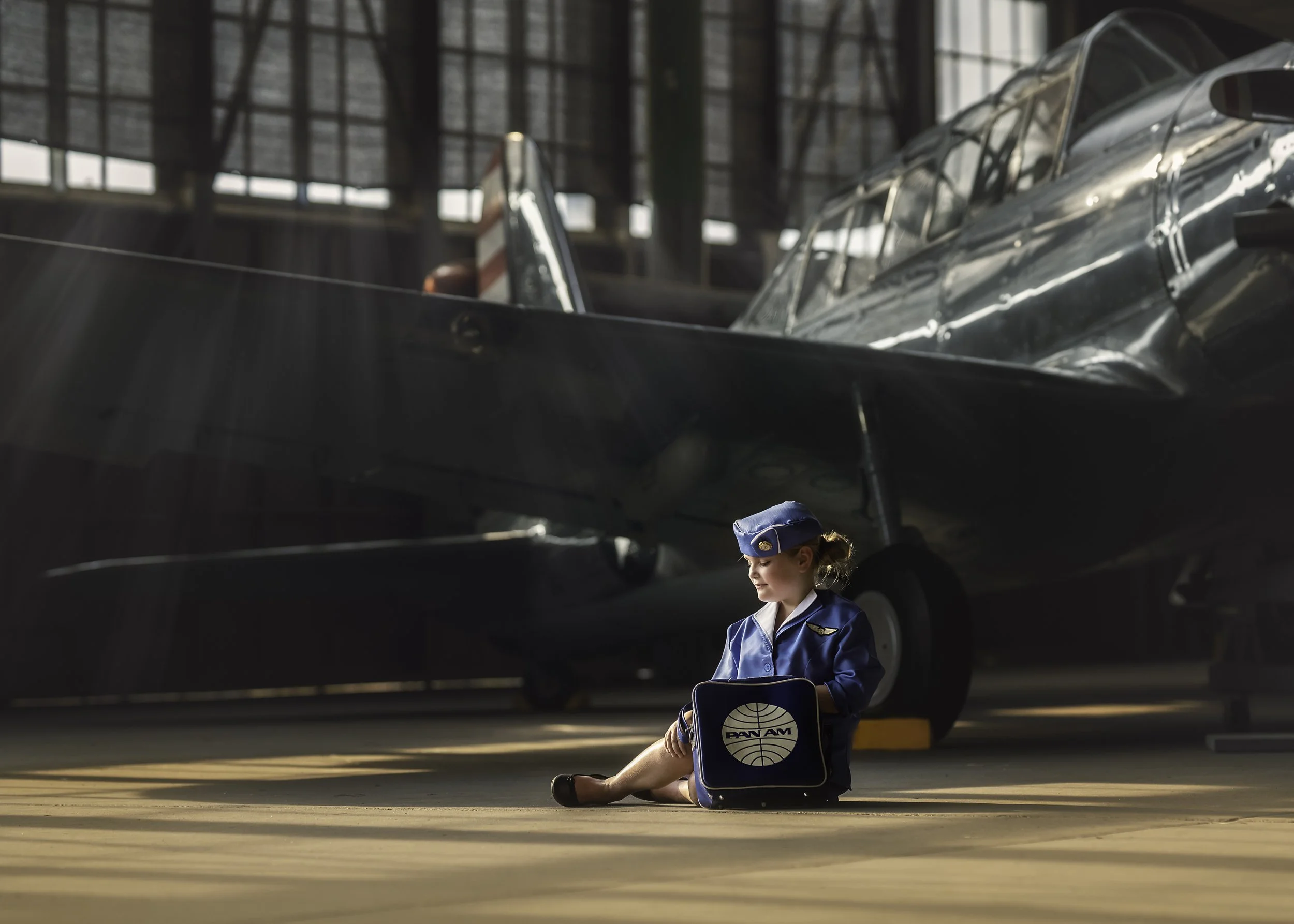 Girl in vintage Pan Am style uniform posing in front of airplane during aviation photoshoot near Cape May New Jersey