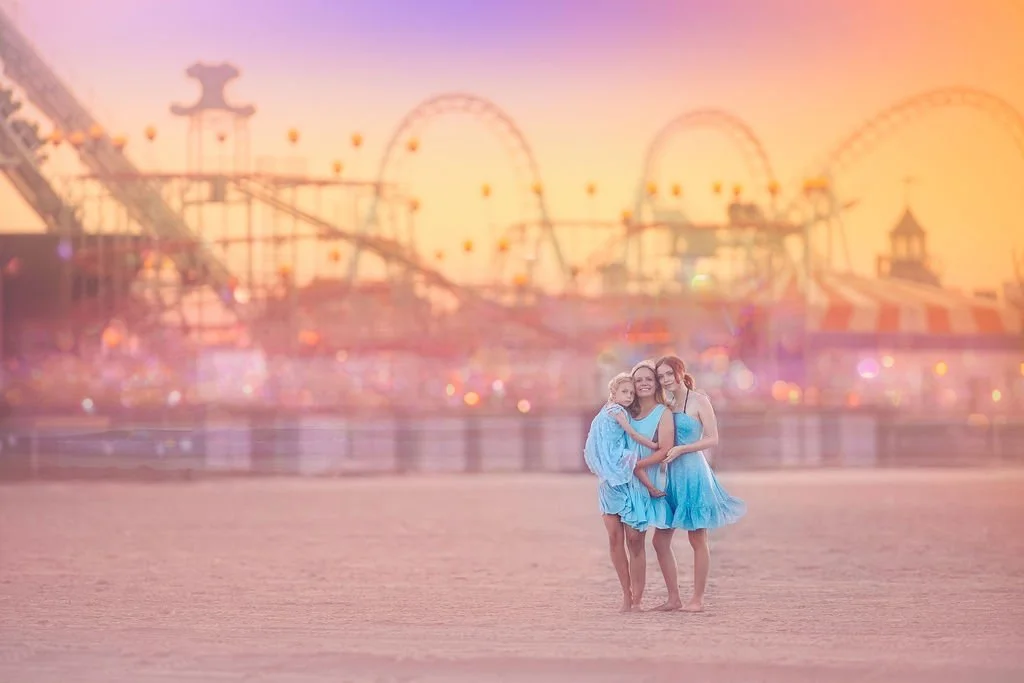 Mom with two daughters in blue dresses on the beach in Wildwood NJ with Morey’s Pier in the background