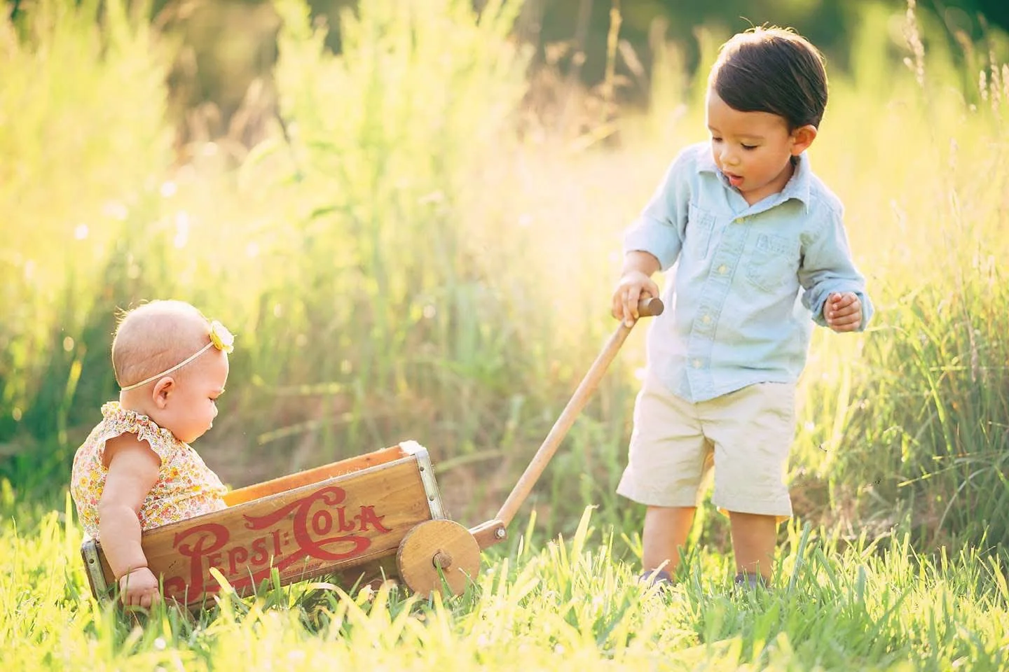 oddler pulling a wagon with a baby sibling during a playful, natural portrait session in New Jersey.