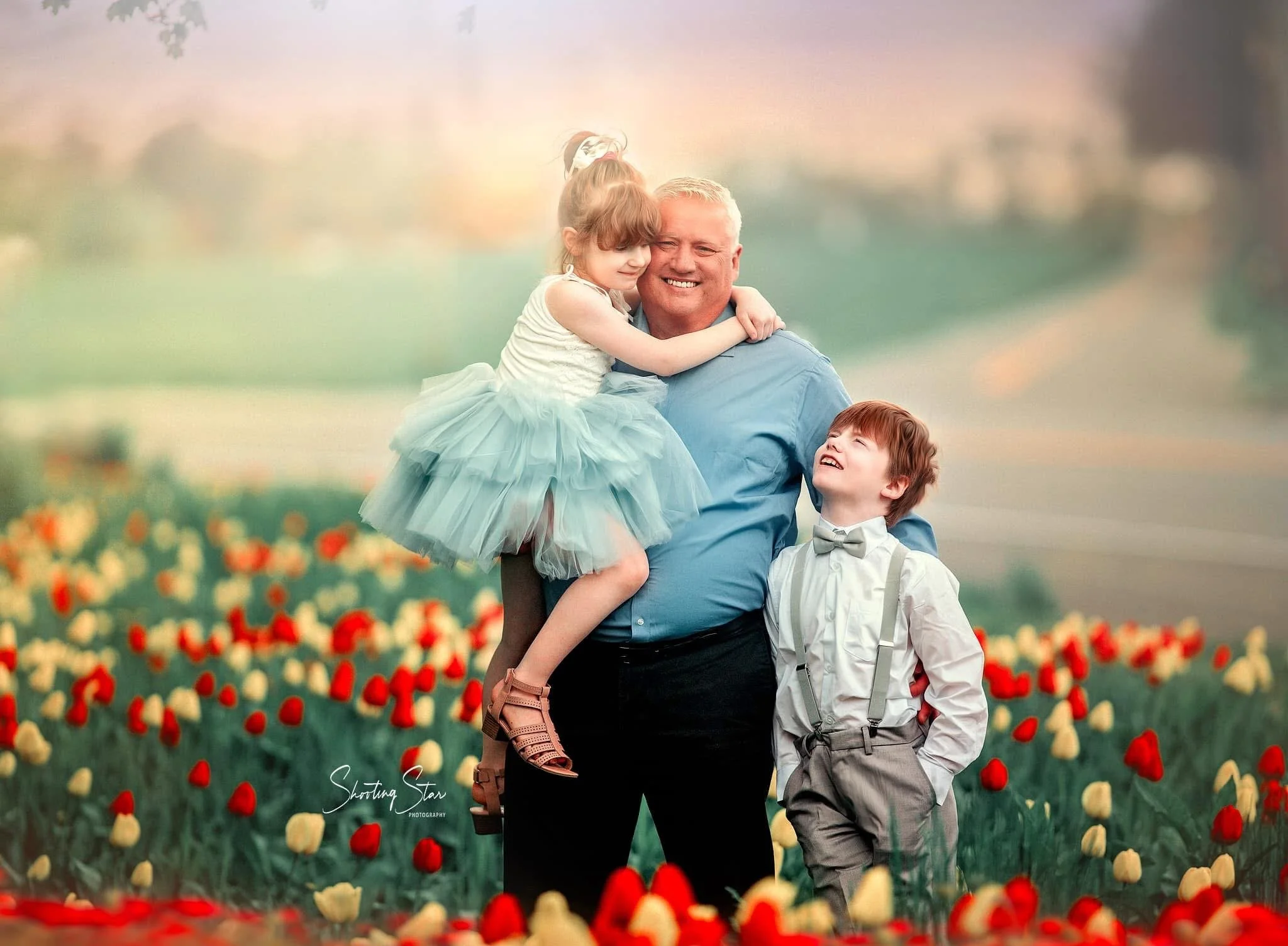 Father with two children standing in a tulip field during spring, photographed by a New Jersey family photographer.