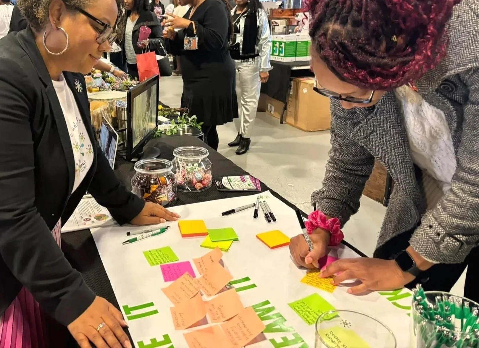 Empact Global facilitating a community engagement session as a participant contributes ideas to a shared sticky-note board.