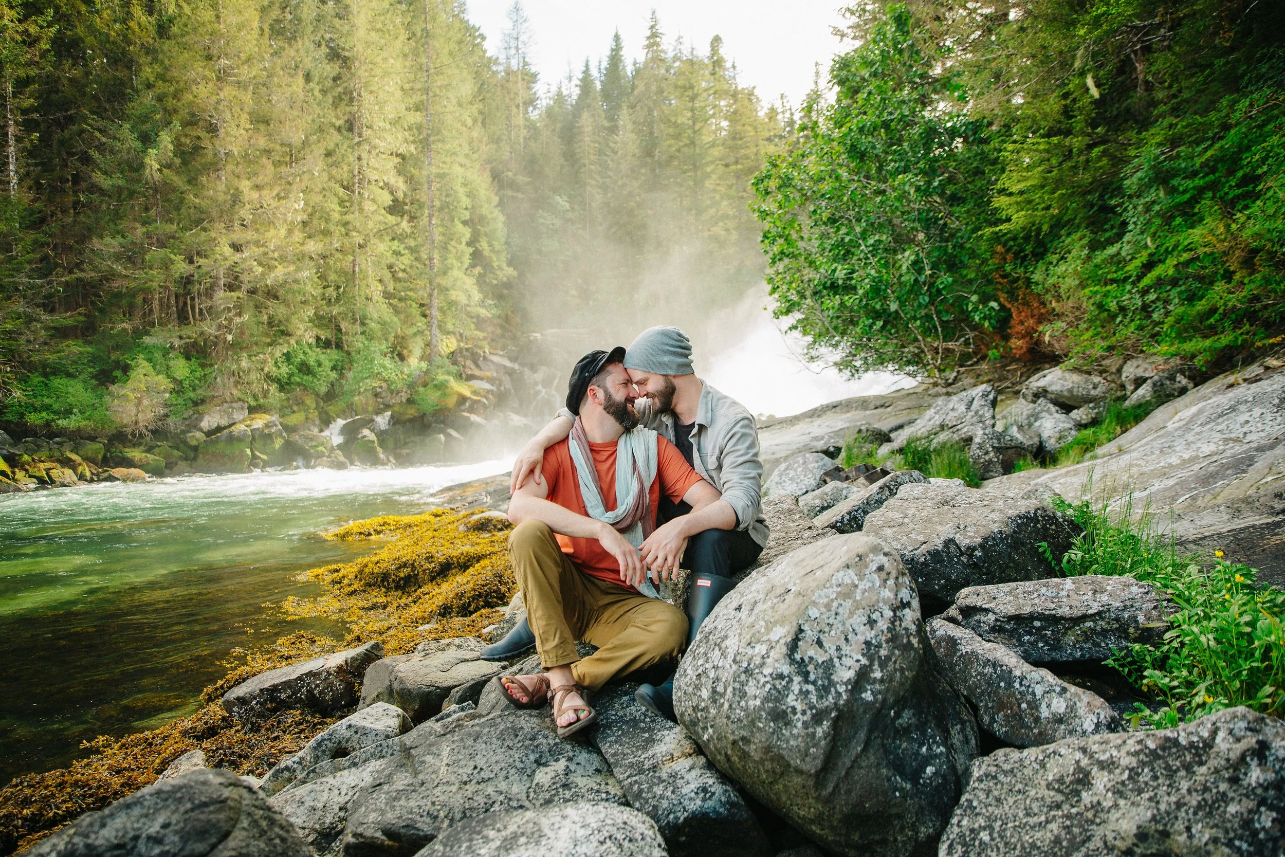Portrait of two grooms engagement session in front of waterfall in southeast alaska